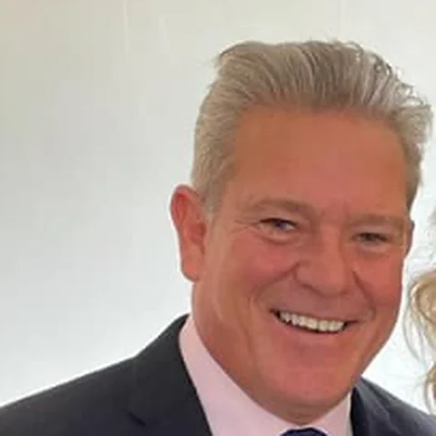 James, founder of SolarSave, smiling, in a dark suit and blue tie