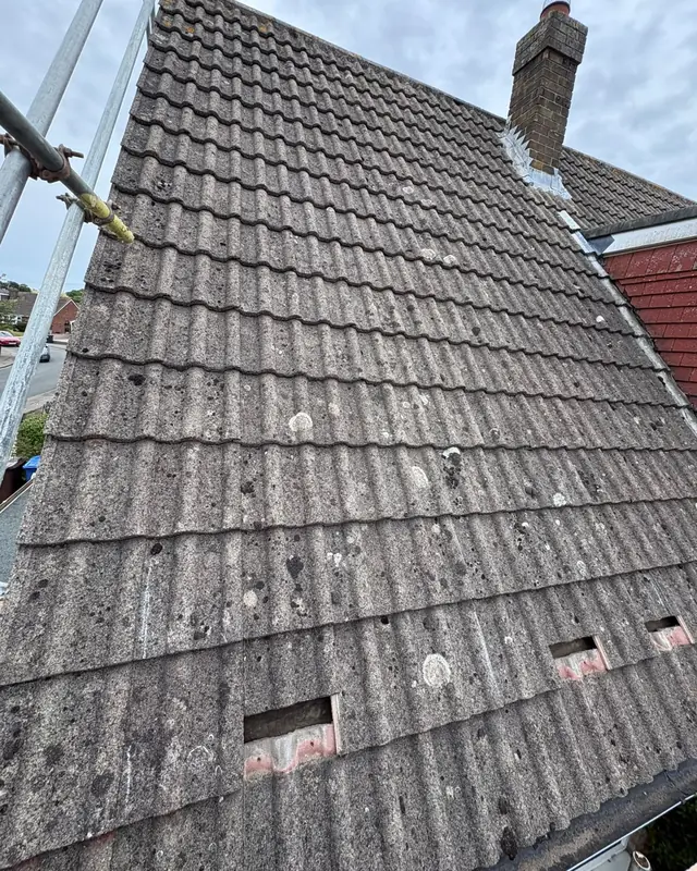 A grey concrete-tiled roof before the install, with a few tiles lifted where the roof hooks will go