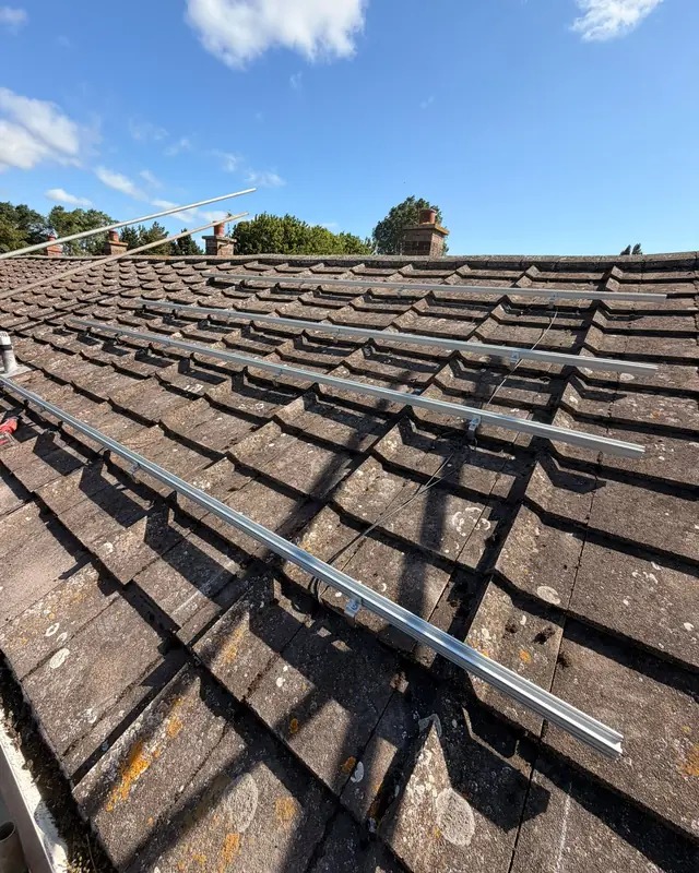 Aluminium mounting rails fixed in rows across a tiled roof, ready for the solar panels
