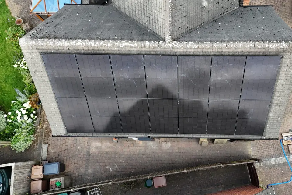 Looking straight down on a grey tiled roof covered by two long rows of black solar panels